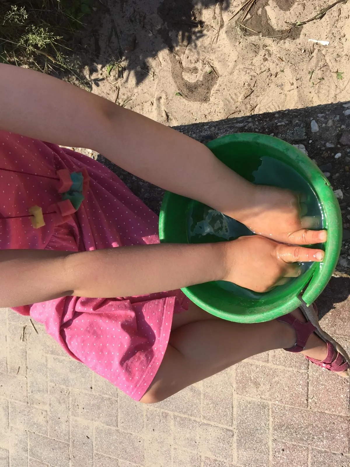 Kind spielt mit Wasser und Sand im Garten