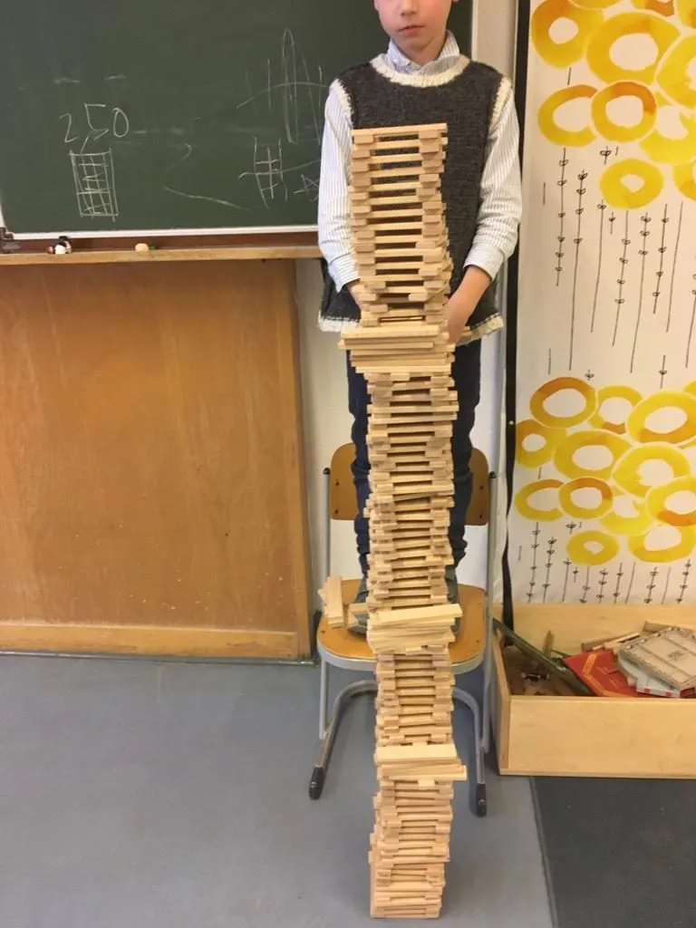 Kind baut einen hohen Turm aus Holzbausteinen